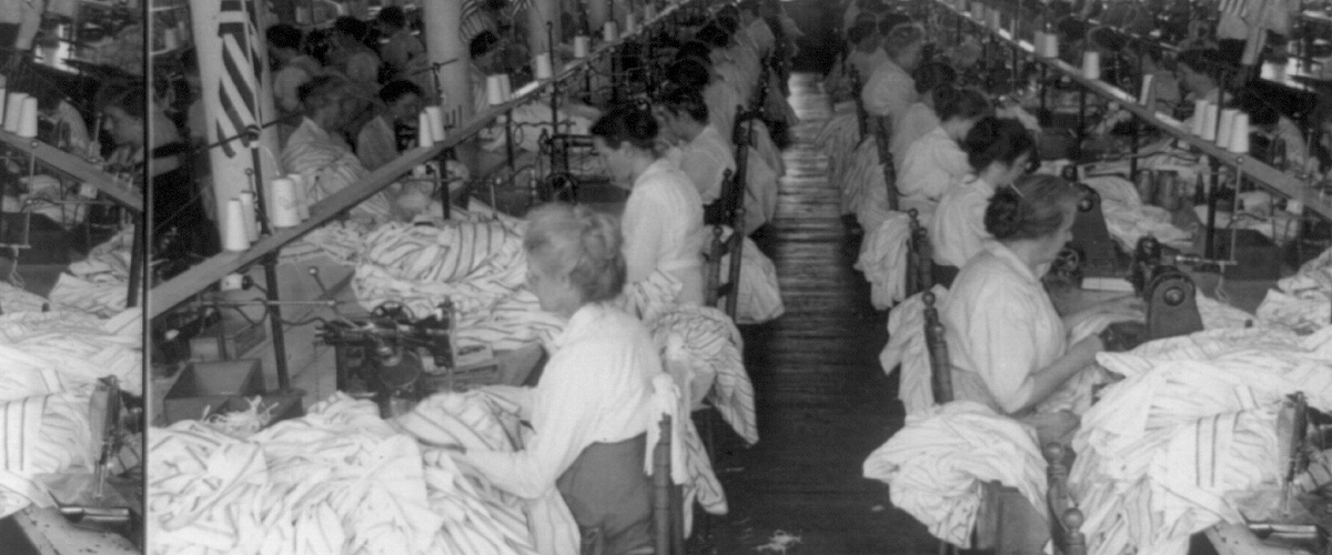 Photograph of a sewing room in a shirt factory in Troy, New York, which would have resembled the tight working conditions of the Triangle shirtwaist factory workers.